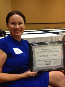 Jennifer Wallace sitting, holding a certficate for 25 years of Chamber of Stockton membership